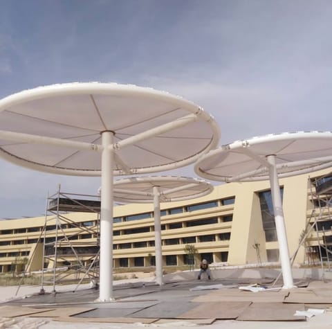 Cluster of circular umbrella shades being installed in front of a building