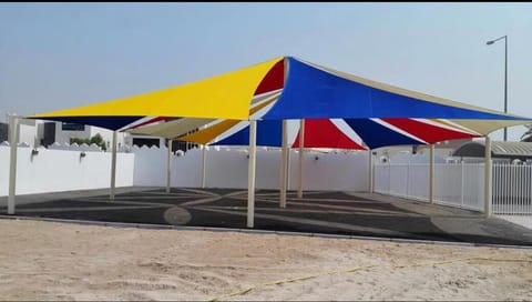 Blue, yellow and red hip shade on steel posts over an open yard