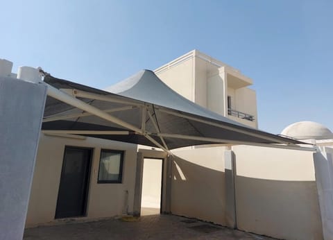 Dark conical canopy shading the entrance of a building