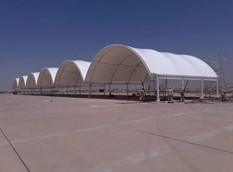 Row of large white arched membrane structures on an open site