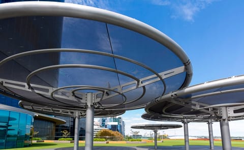 Round umbrella canopies with steel rings beside a glass building