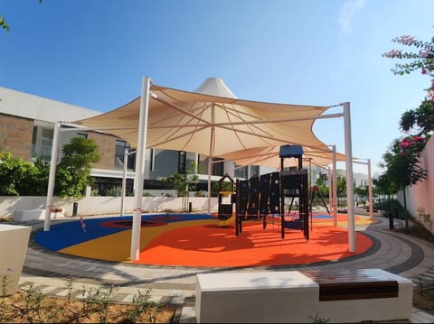 Sand shade sail on steel masts above a play frame and orange flooring