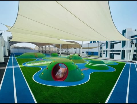School rooftop play area under white shade sails with a running track